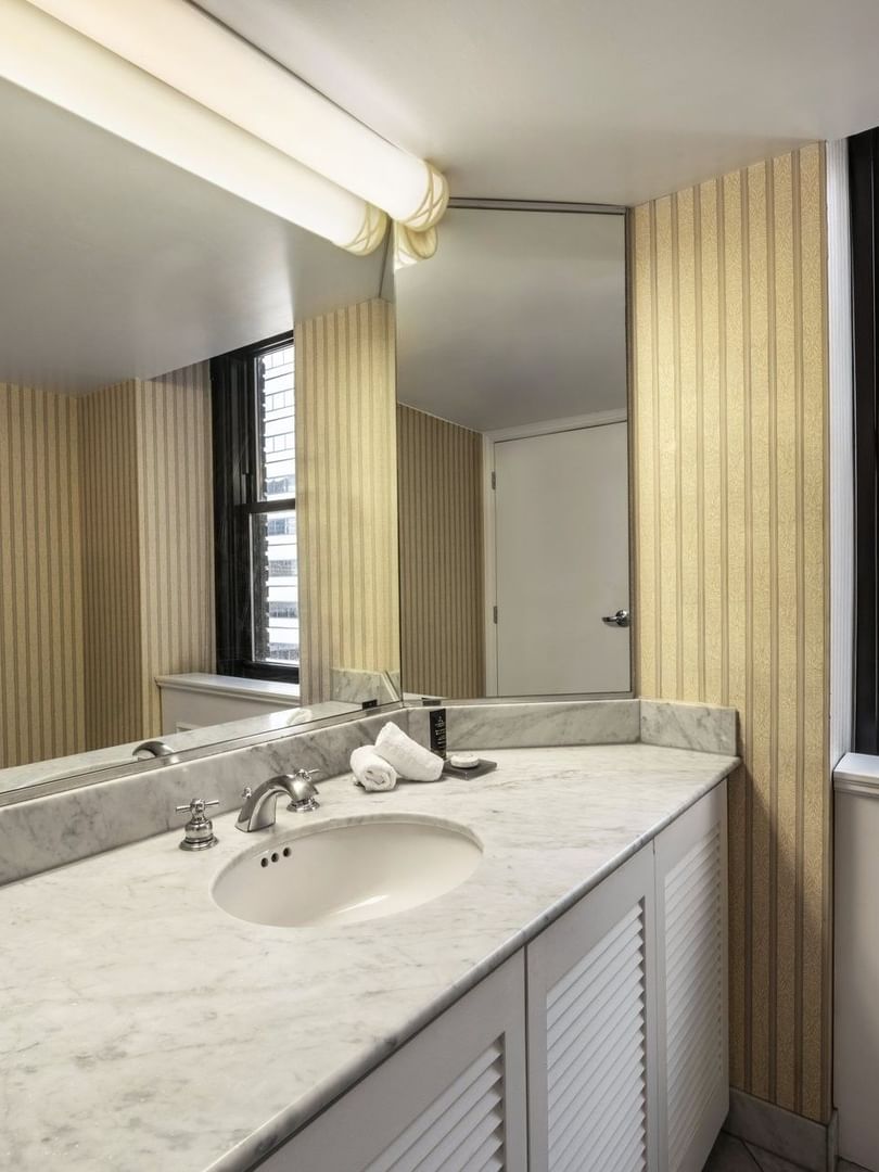 Speciality Suite bathroom featuring a marble vanity with a mirror by the window at Warwick Allerton Chicago