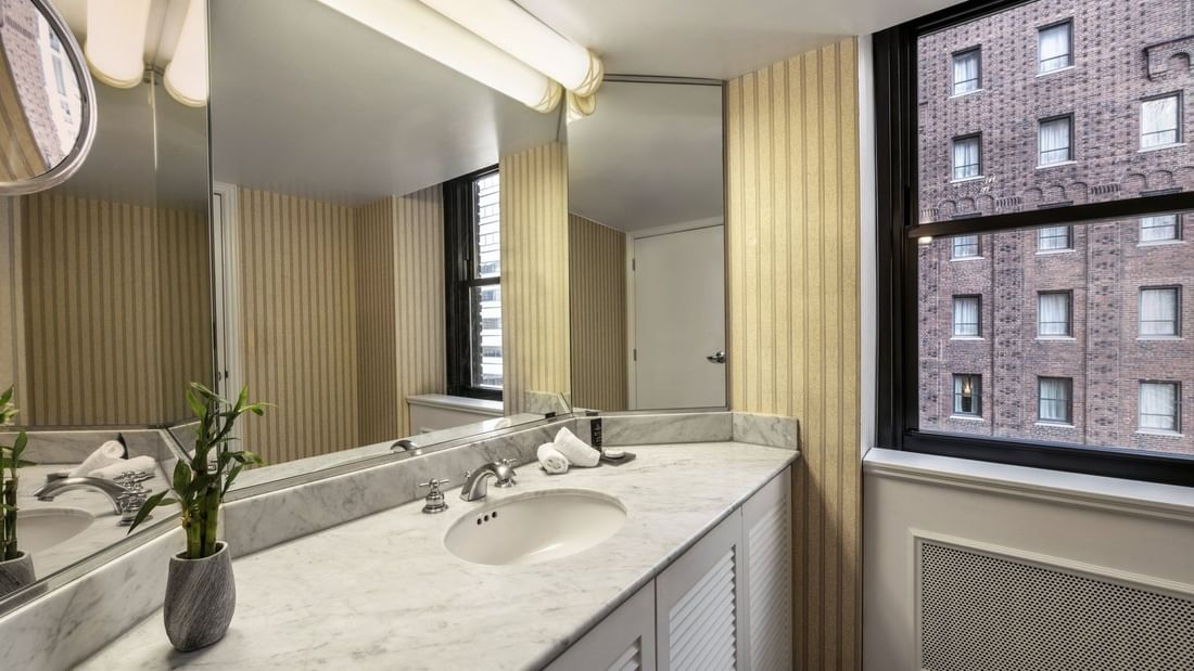 Speciality Suite bathroom featuring a marble vanity with a mirror by the window at Warwick Allerton Chicago