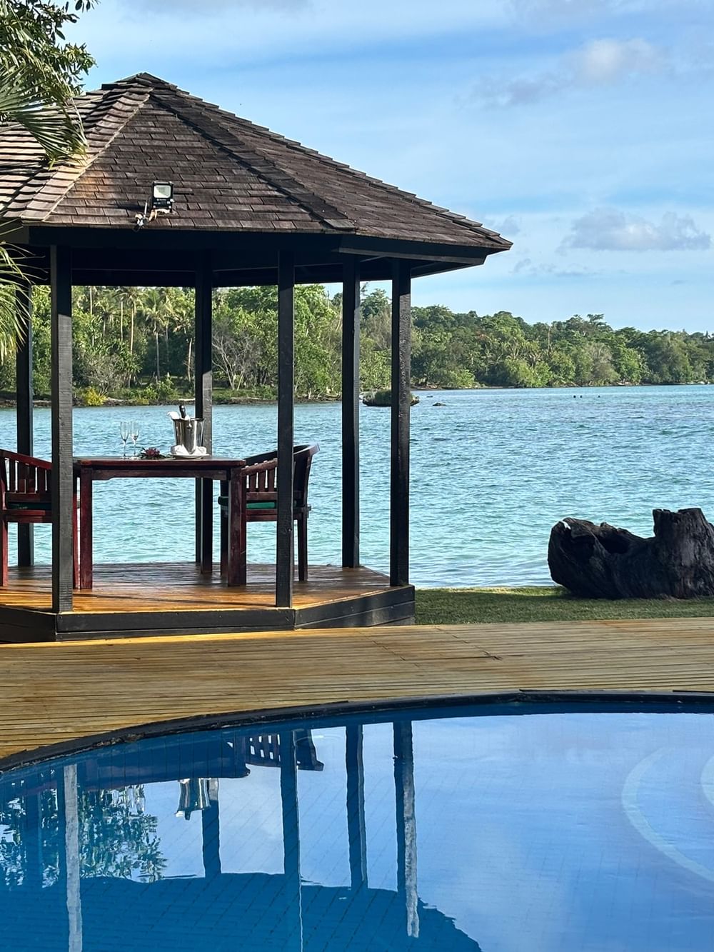Gazebo with table and chairs next to a pool and water view at Warwick Le Lagon Efate.