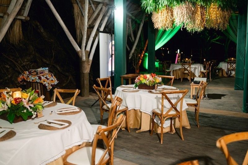 Dining tables under a thatched roof surrounding a dance floor at Morgan's Rock Reserve & Ecolodge