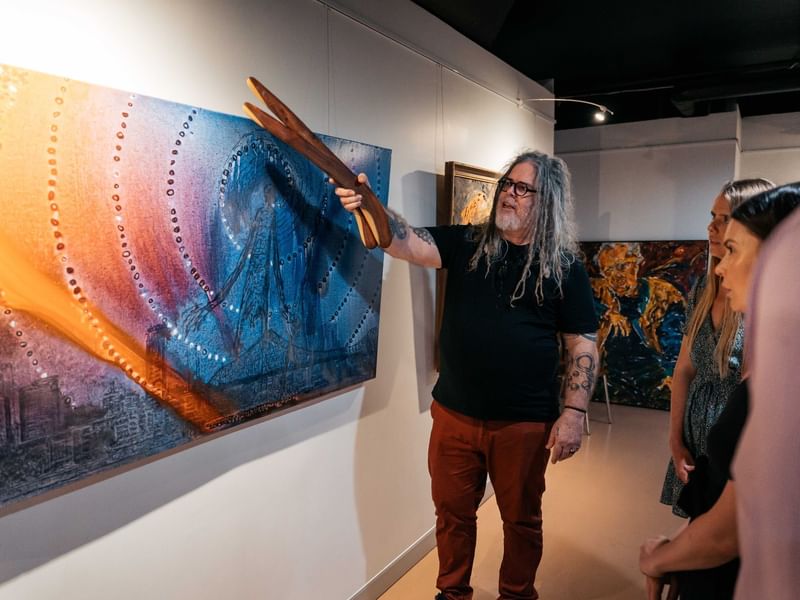 First nations man showing a painting at Birrunga Gallery & Dining near Sofitel Brisbane Central