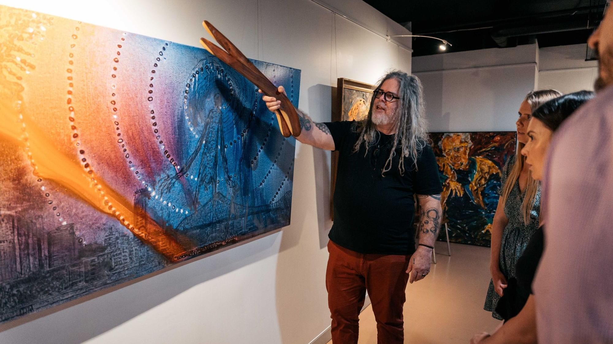First nations man showing a painting at Birrunga Gallery & Dining near Sofitel Brisbane Central