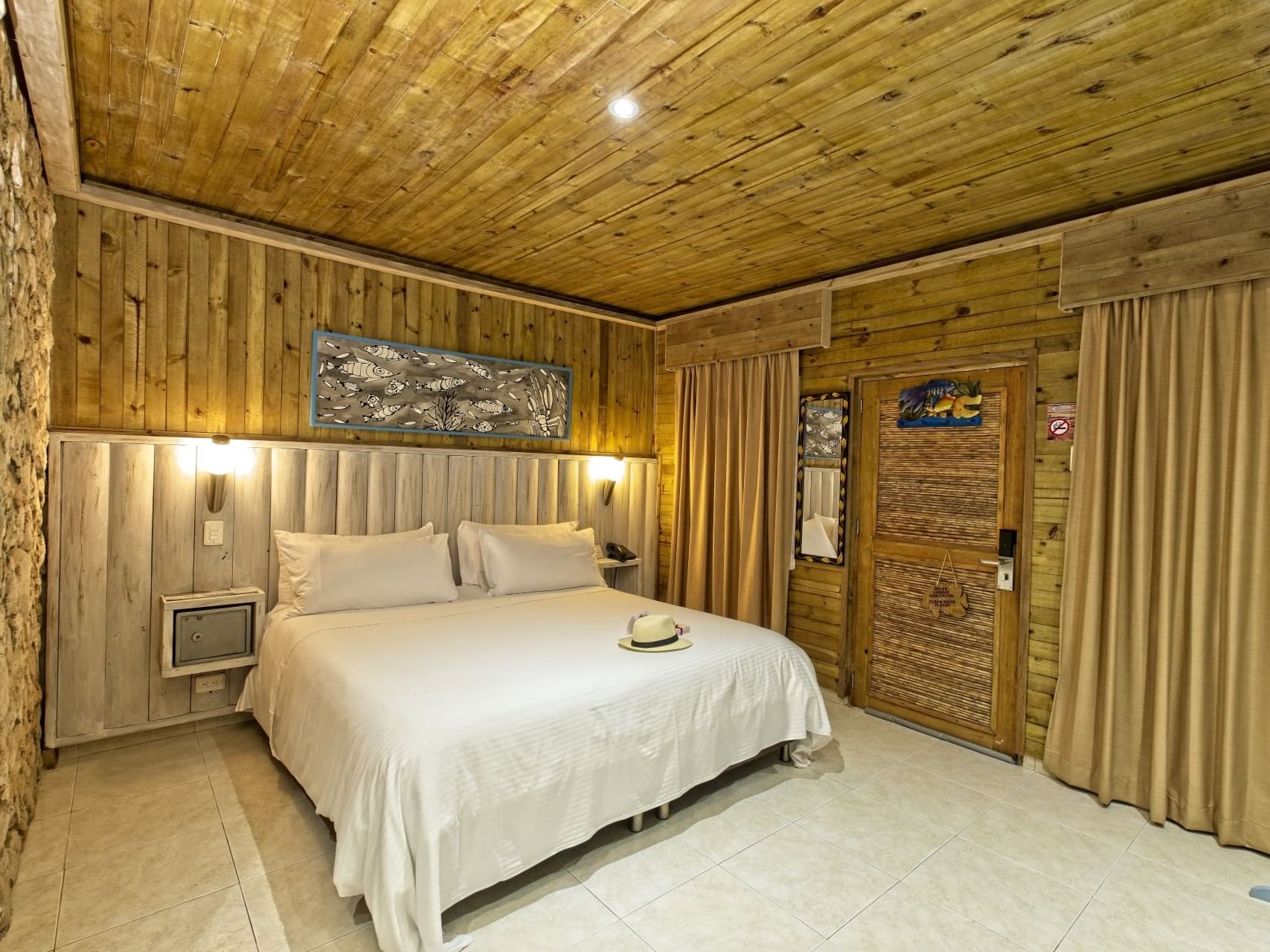 A cozy bed with side lamps and warm wooden walls in Standard room at Hotel Isla Del Encanto