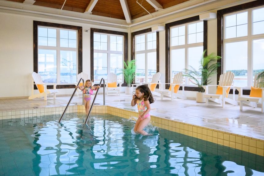 Children playing in an indoor pool by white lawn chairs at Rodd Miramichi River,best places to stay in Miramichi
