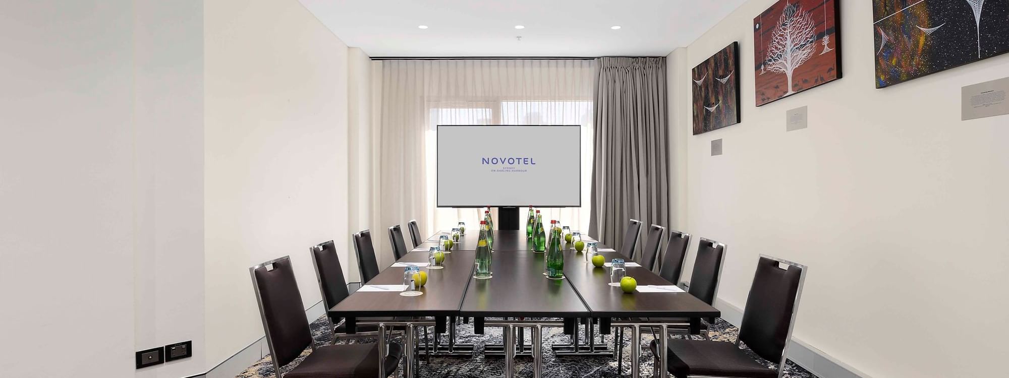 Boardroom set-up facing the projector screen in The Mudgee Boardroom at Novotel Sydney on Darling Harbour