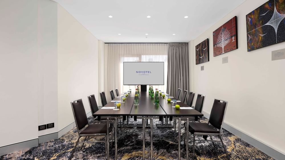 Boardroom set-up facing the projector screen in The Mudgee Boardroom at Novotel Sydney on Darling Harbour