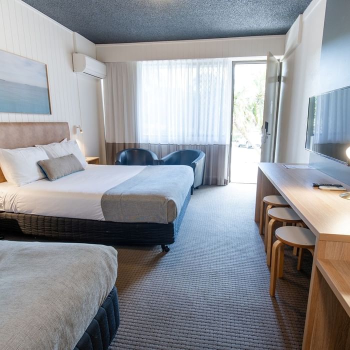 Comfortable hotel room with two beds, a desk, and a balcony at Mercure Charlestown.