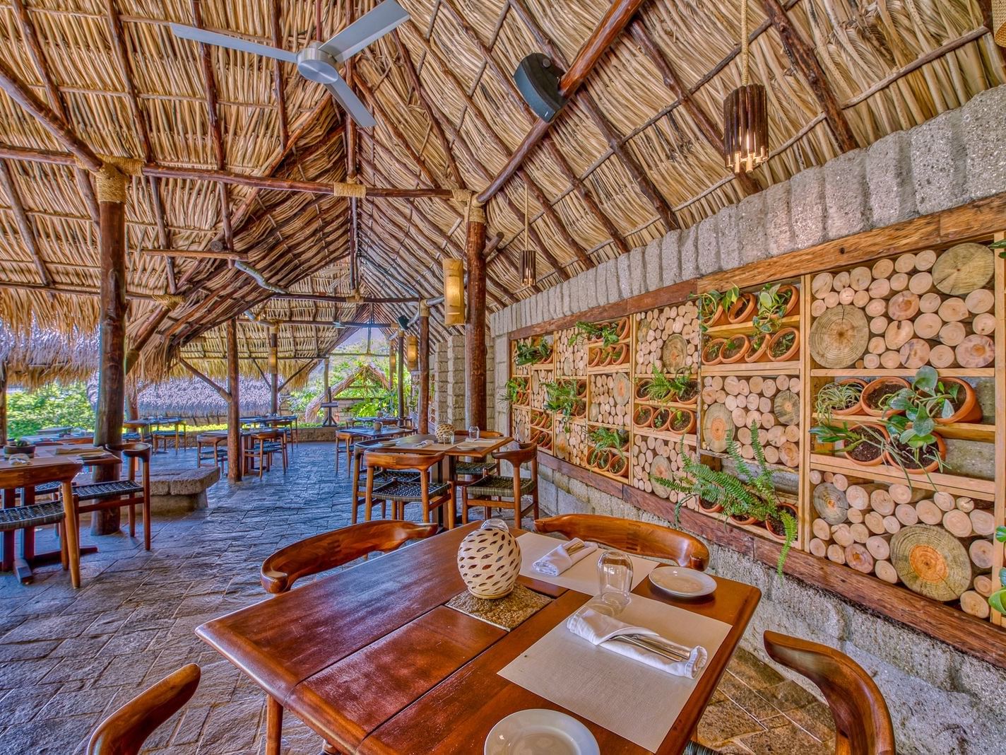 Wooden tables surrounding a plant wall under a peaked roof in La Bastide Restaurant at Morgan's Rock Reserve & Ecolodge