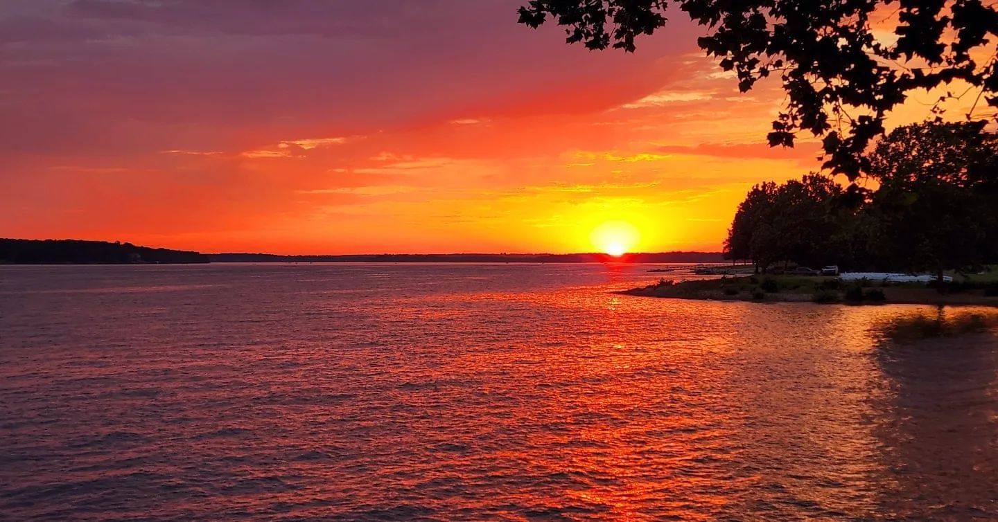 Vibrant sunset casts orange and pink hues over a calm lake near Shangri-La Monkey Island