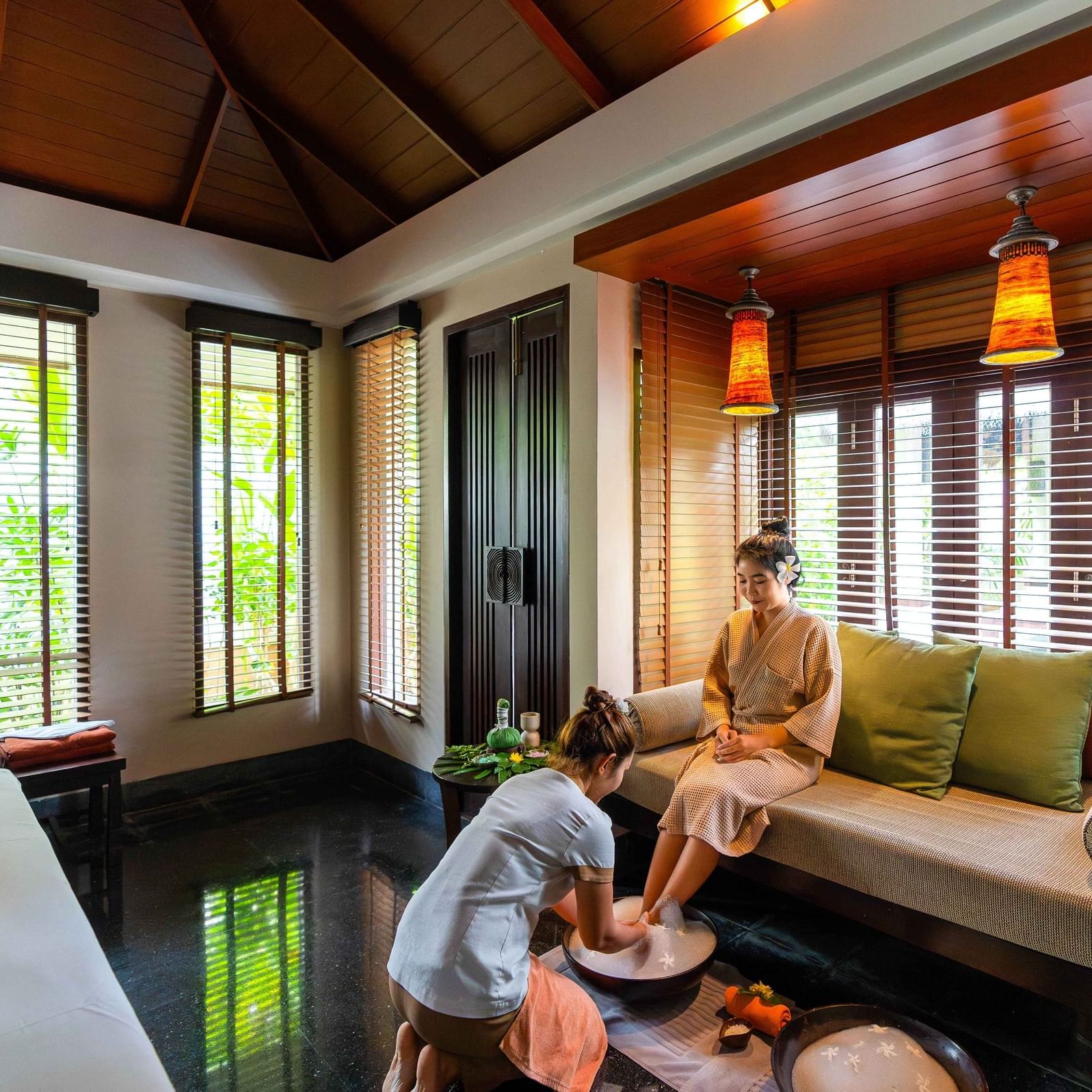 A therapist is preparing the guest's feet by giving them a gentle clean before beginning the spa treatment.