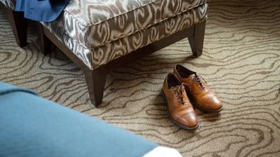 Close-up of men's leather brown shoes by a lounge in a Room at Paramount Hotel Portland