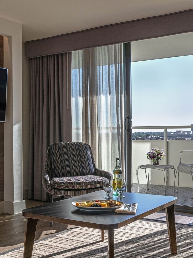 Modern living room with a TV by a striped chair under a wood wall near a balcony in Premier Suite at Warwick Denver