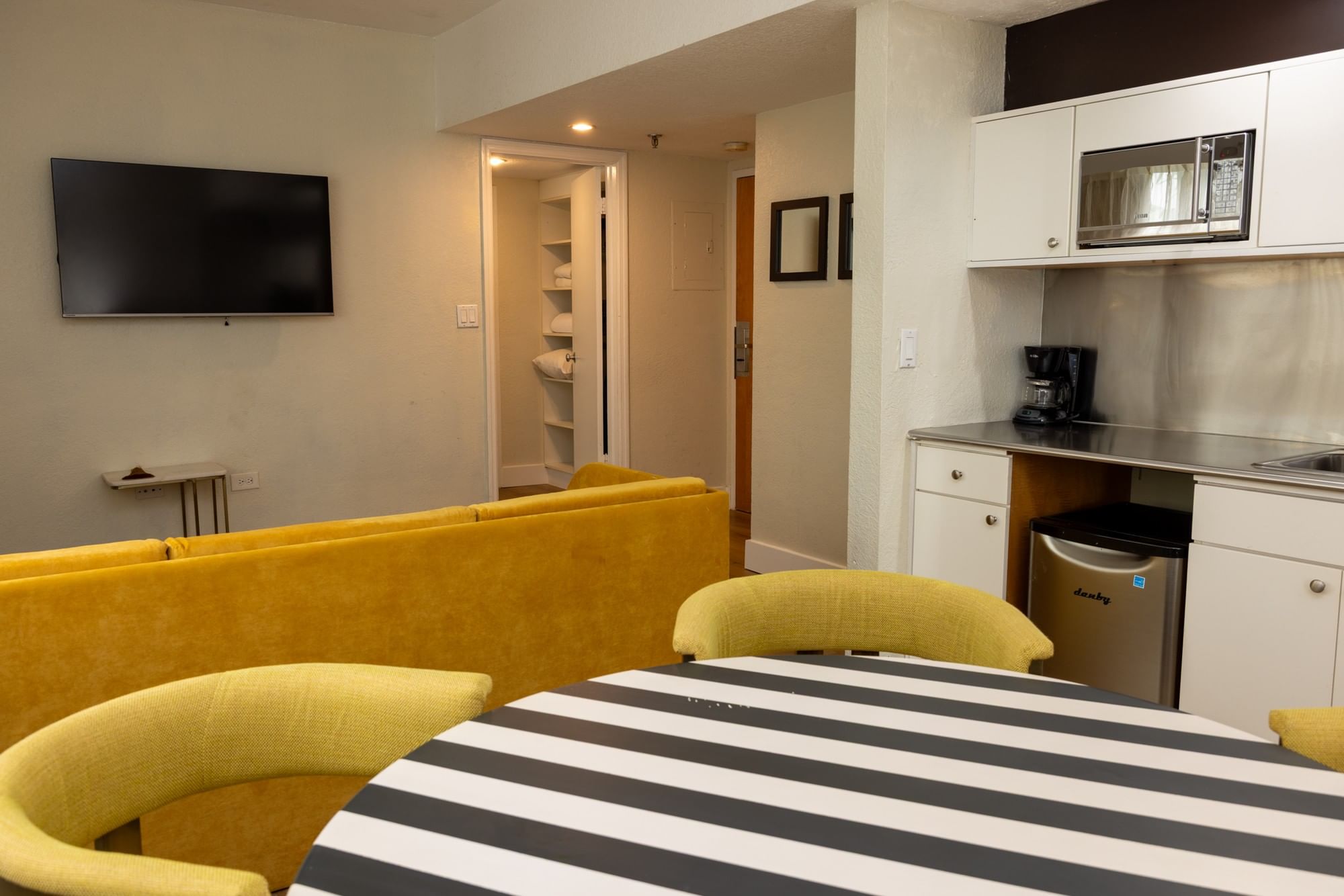 A wide view of a hotel room's living area, kitchenette, and dining space.