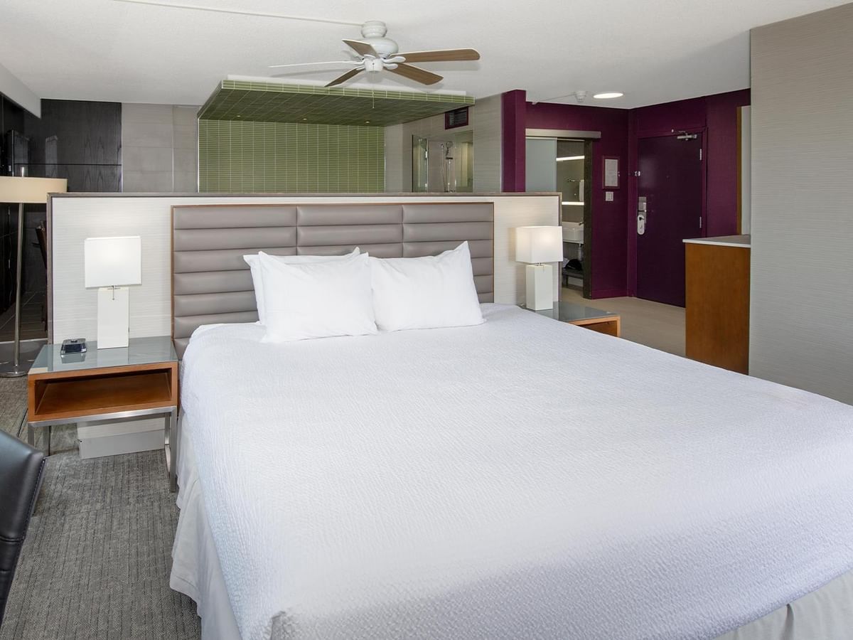 Modern junior suite with king bed, white linens, ceiling fan, and open bathroom at Coast Prince George Hotel