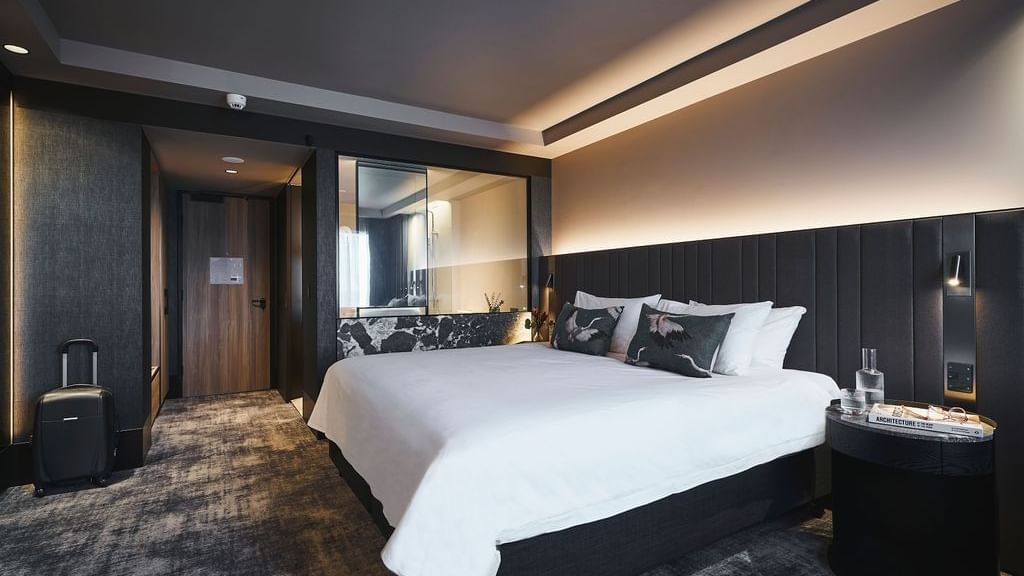 Premium Superior Room with king bed, dark paneled walls, ambient lighting, and modern decor at Pullman East Melbourne.