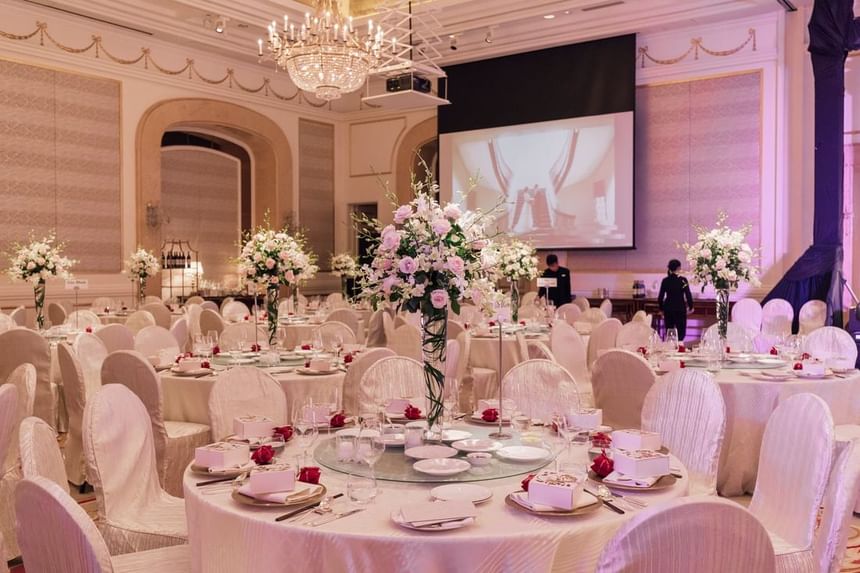 Elegant banquet hall decorated with floral centerpieces, round tables set for a wedding at Park Hyatt Saigon