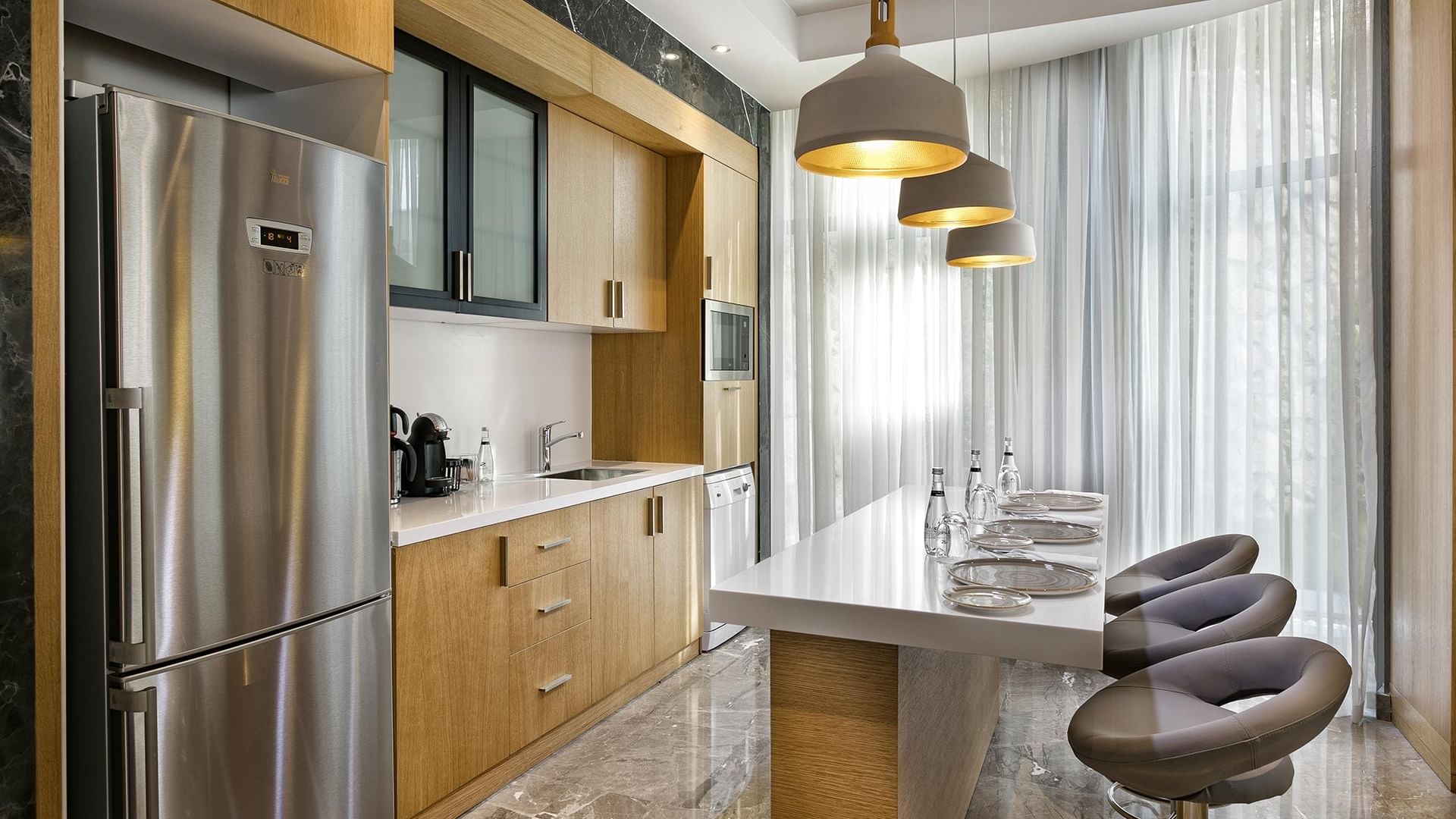 Kitchen area equipped with bar stools & refrigerator in Presidential Villa at Titanic Luxury Collection Bodrum