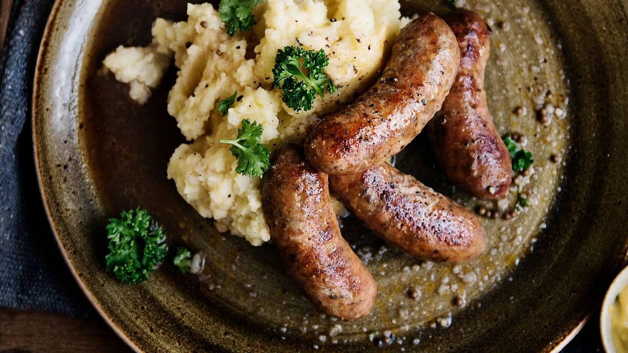 Close-up of a plate of bangers and mash served in Bonanza Dining Room at Midnight Sun, a Coast Hotel