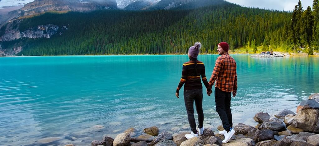 Couple walking beside turquoise lake in Banff