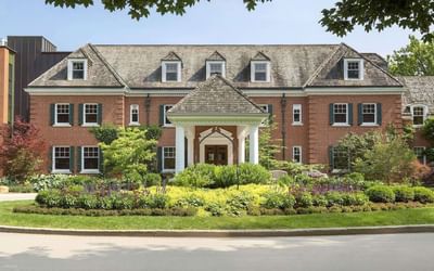 Wide view of the historic brick facade, gardens, and main entrance at Spencer Hotel, among historic hotels Ontario