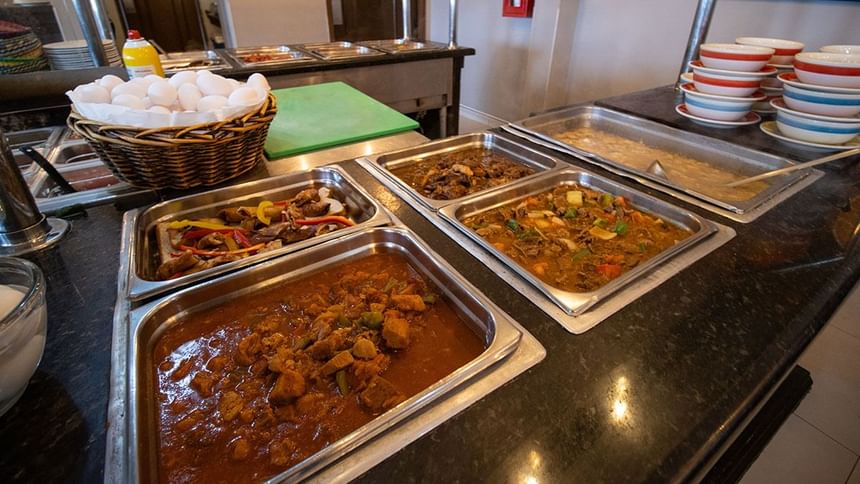 Breakfast buffet with seasoned meat dishes in steel trays beside a basket of eggs in Palmira Cafeteria at Araiza Calafia