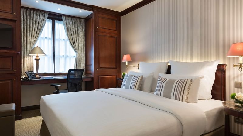 Bed area and workspace with window in Classic Room at Warwick Brussels