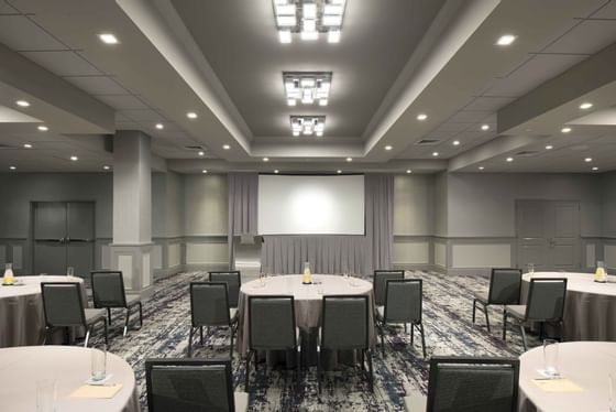 banquet room with round tables, chairs and projector screen