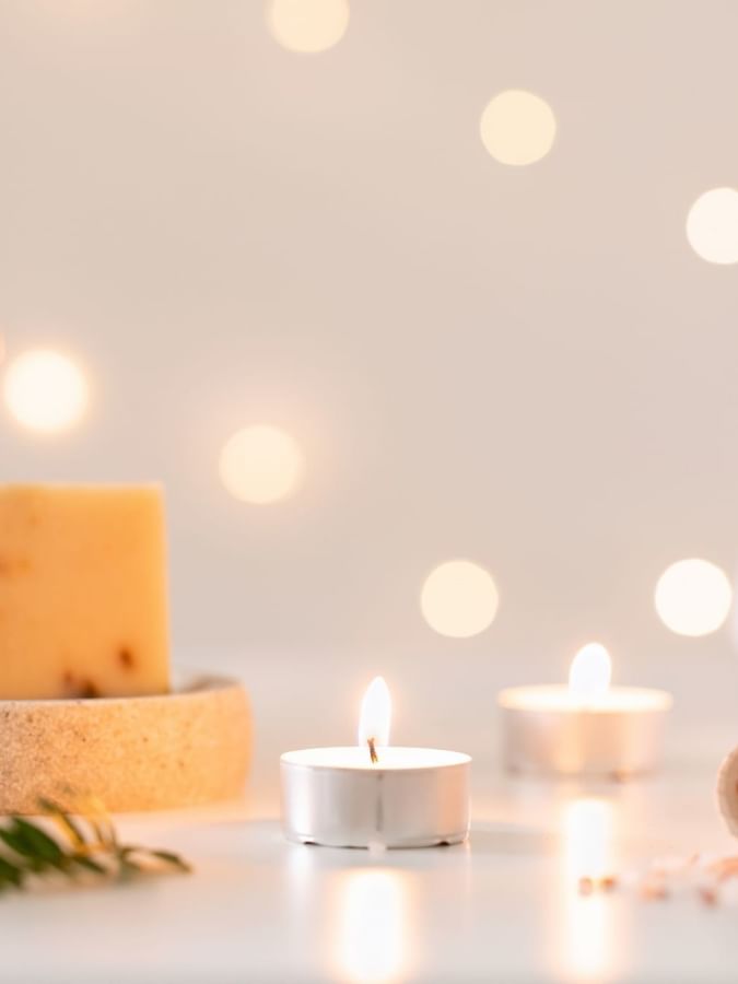 Lit candles by a bar of soap under soft bokeh lights surrounding sea salts at Warwick Paradise Island Bahamas