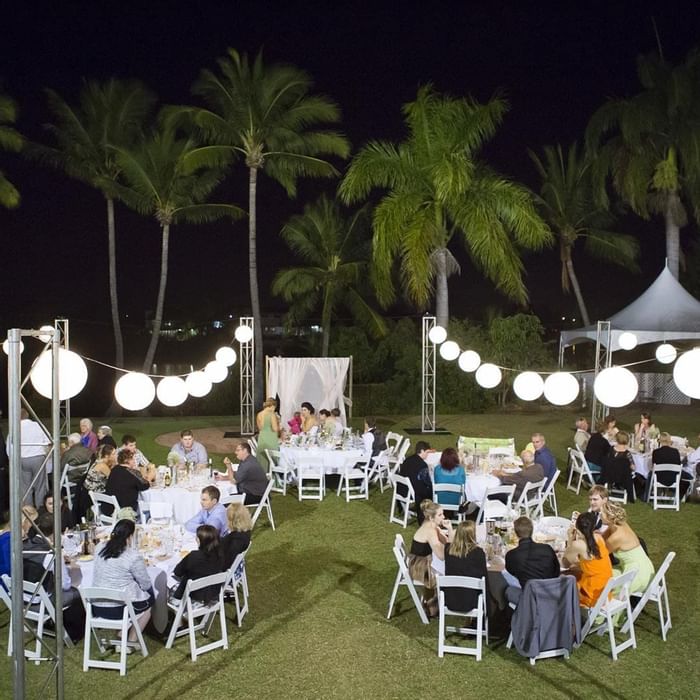 Guests at well-lit outdoor venue with round tables and hanging lanterns in Mercure Hotel Townsville