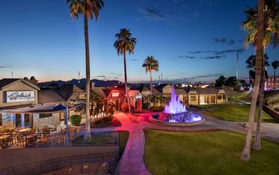 Evening view of illuminated fountain and palm-lined courtyard with Splash Bar and Grill at London Bridge Resort