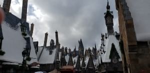 A picture of the Wizarding World of Harry Potter Land with fake snow on the tops of their buildings.