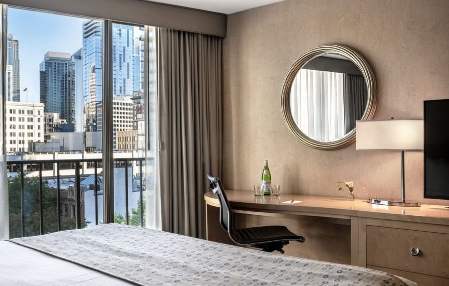 Wooden desk featuring a black office chair under a round mirror by a large window in Executive Room at Warwick Seattle