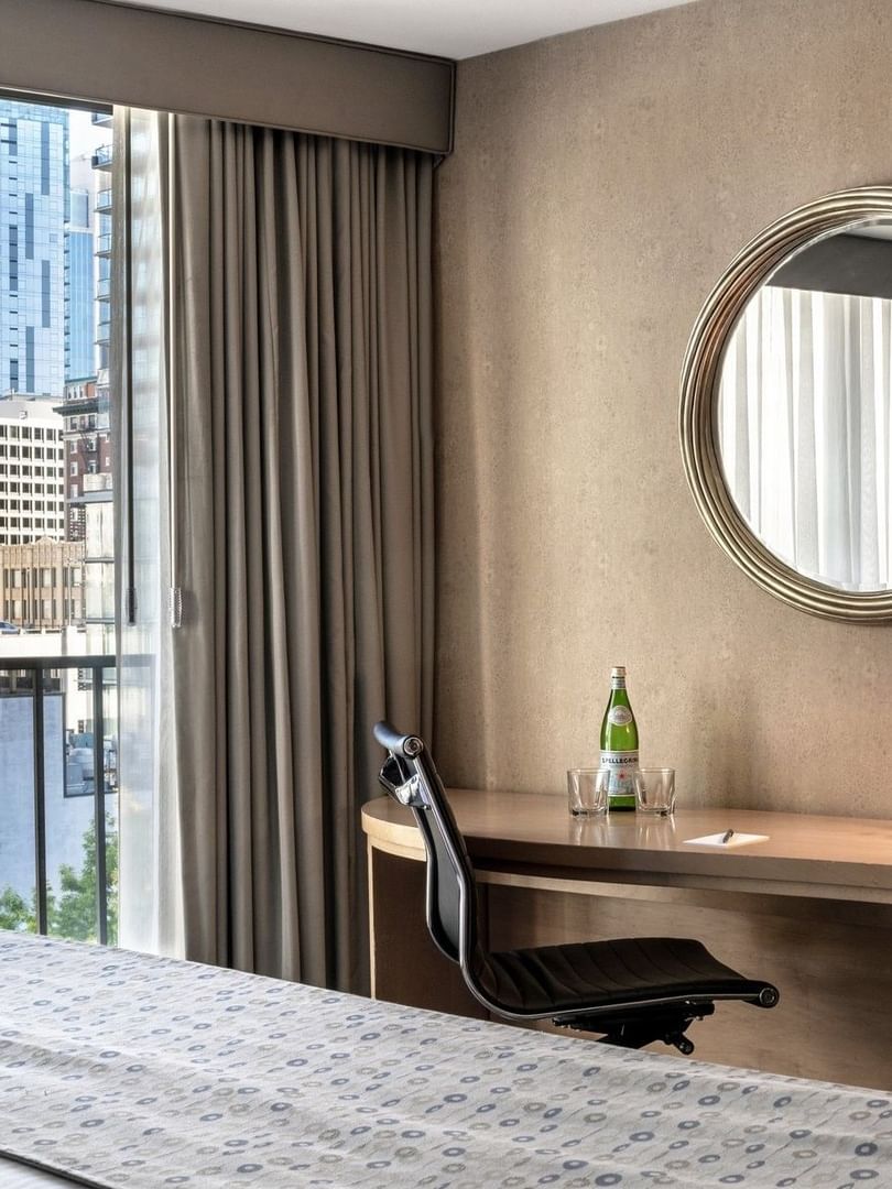 Wooden desk featuring a black office chair under a round mirror by a large window in Executive Room at Warwick Seattle