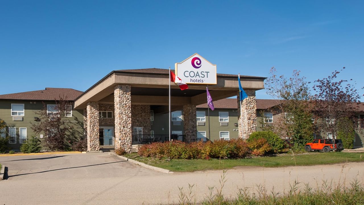 Modern hotel exterior with stone pillars, covered entrance, and prominent Coast Hotels signage at Coast Edson Hotel.