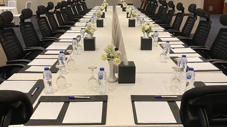Crystal Meeting Room U shape setup with a table, chairs, floral centerpieces, and notepads at Warwick Hotels and Resorts