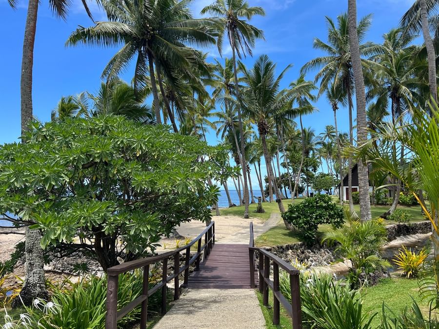 Wooden bridge leading to tropical beach with ocean view at Tambua Sands Beach Resort Fiji.