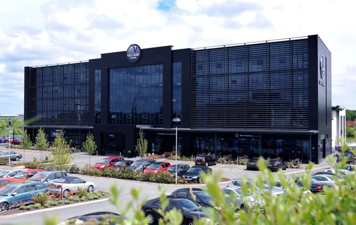 An exterior view of the hotel & car park at Village Hotels