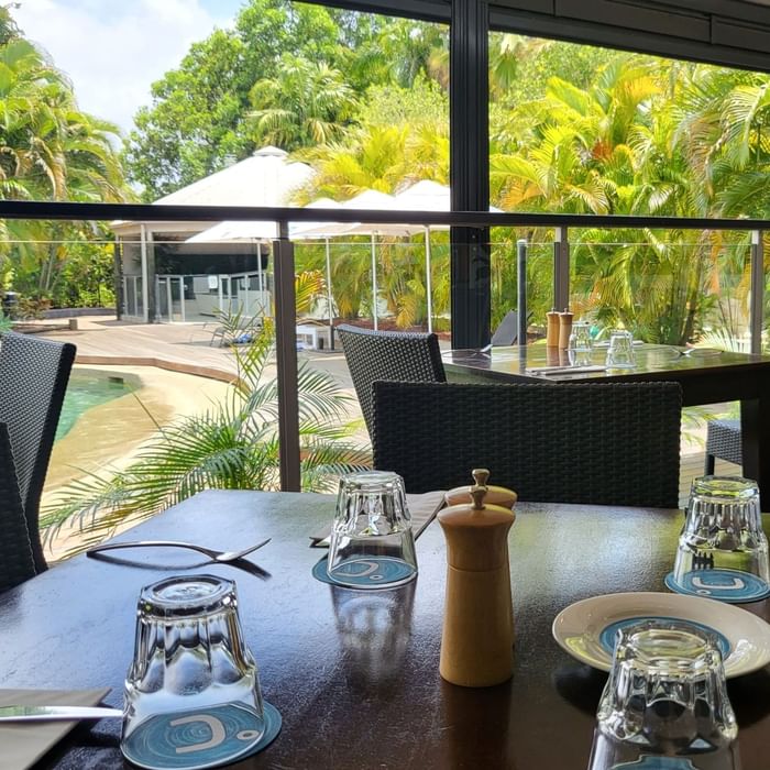 Dining area with wicker furniture overlooking the pool in Celsius Restaurant & Bar at Mercure Hotel Townsville