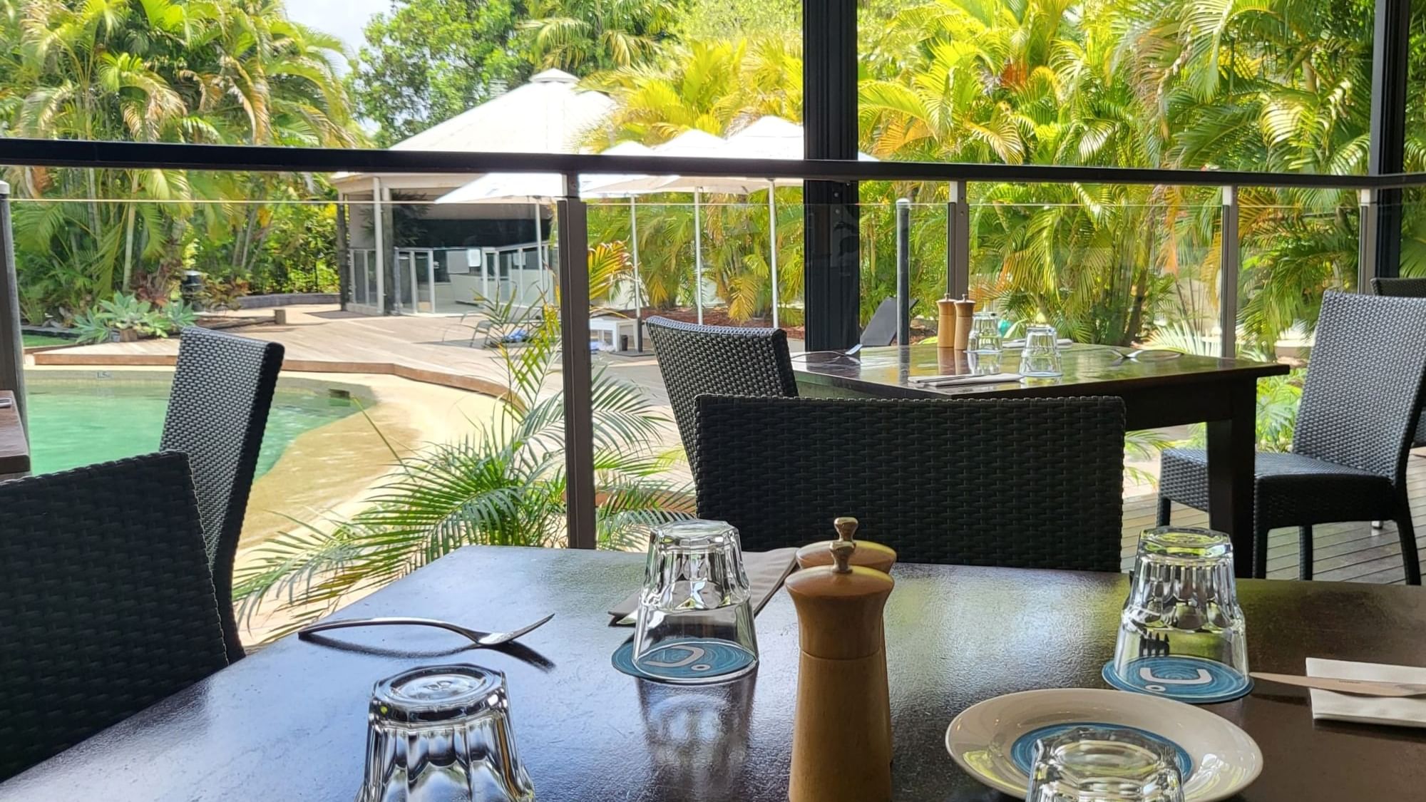 Dining area with wicker furniture overlooking the pool in Celsius Restaurant & Bar at Mercure Hotel Townsville
