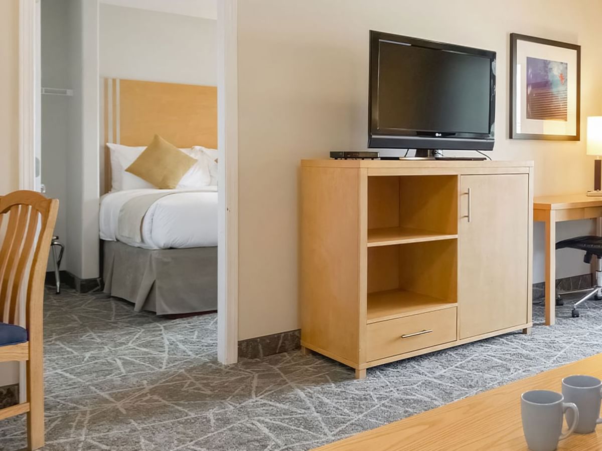One-bedroom suite with separate sleeping and living areas, featuring a TV and desk.