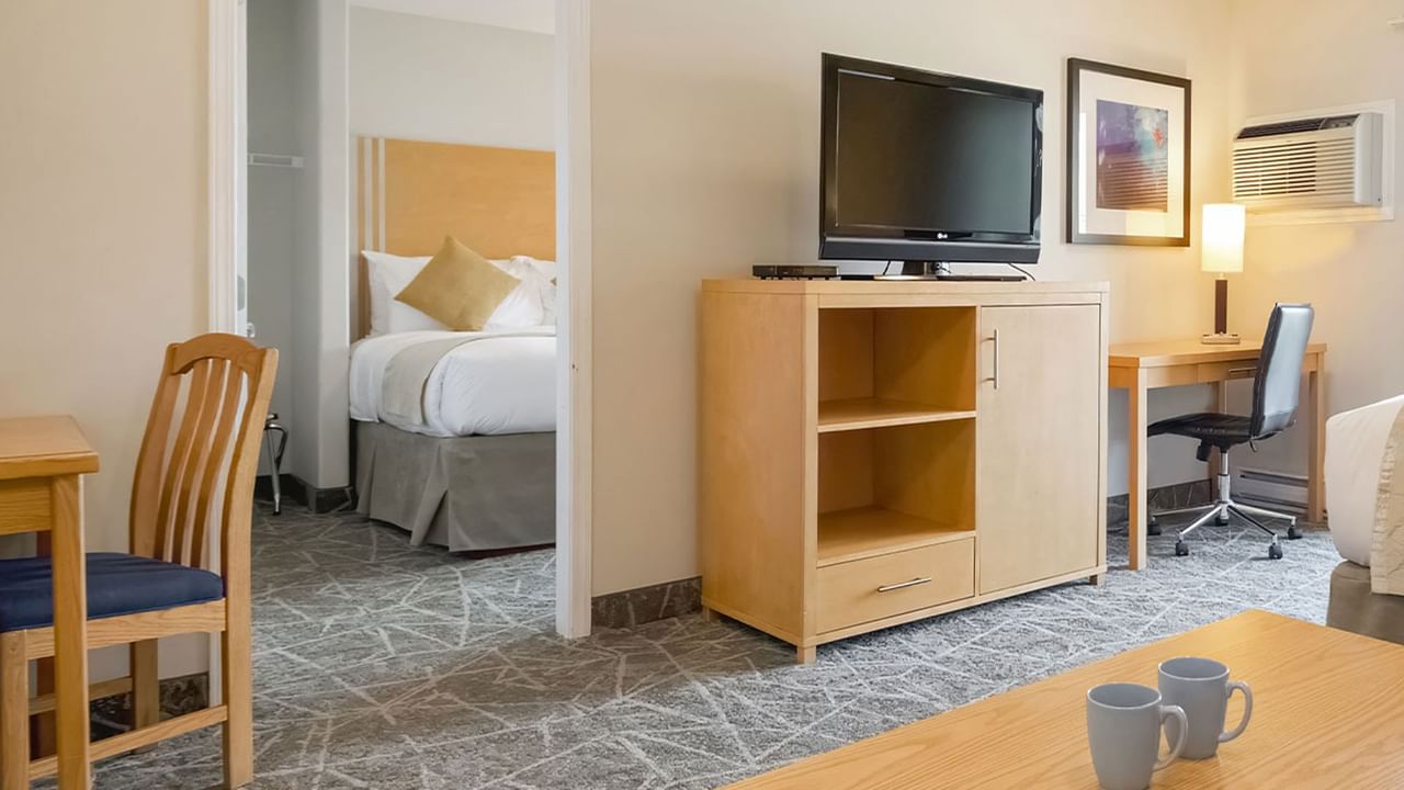 One-bedroom suite with separate sleeping and living areas, featuring a TV and desk.