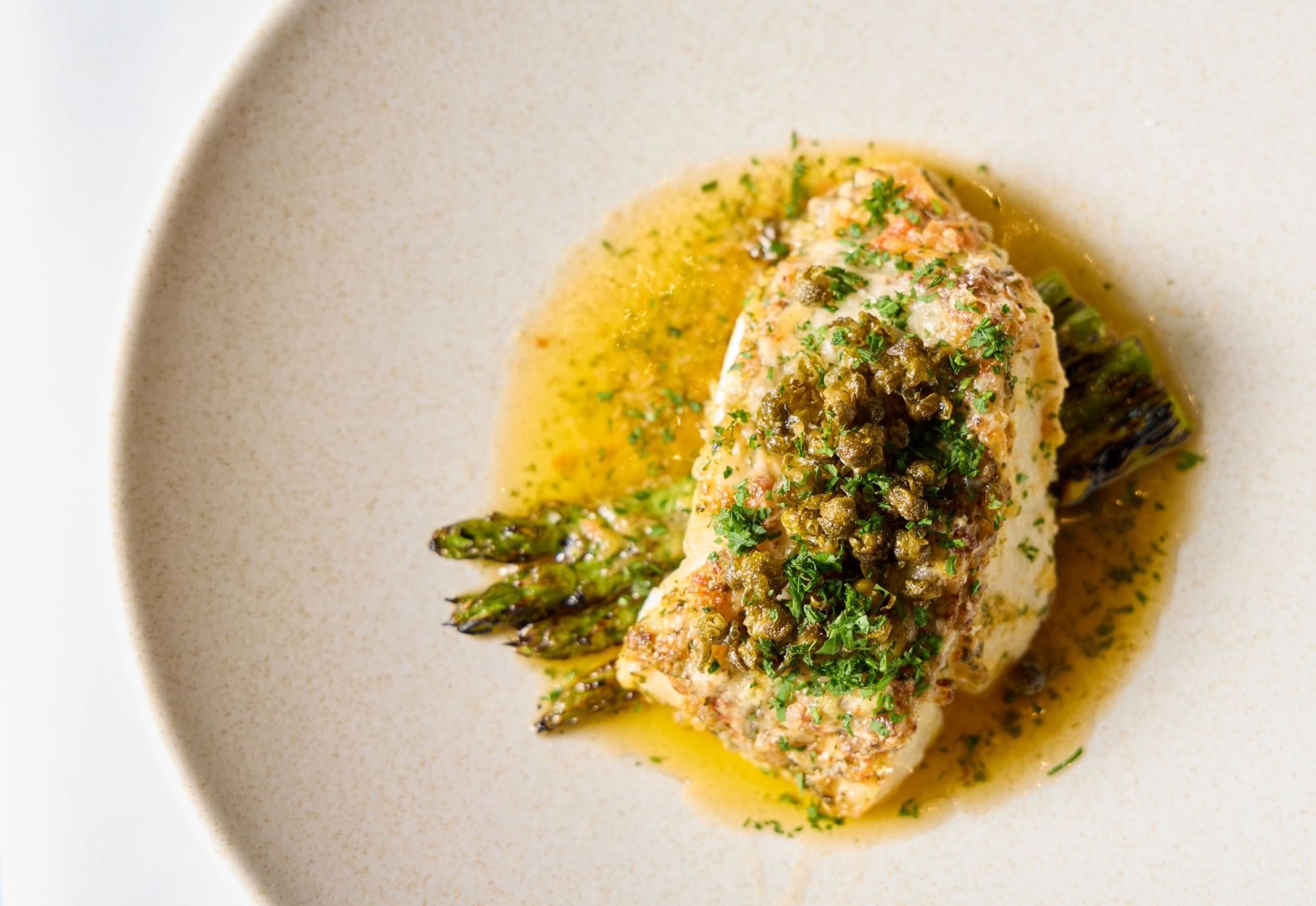 A perfectly cooked fish fillet topped with capers and herbs in Whitcomb's Terrace at The Londoner Hotel