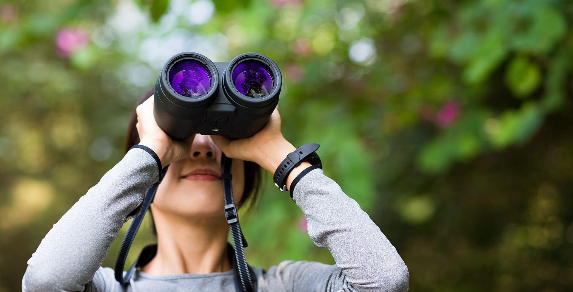 Girl looking through binocular at woods near Coast Fort St.John