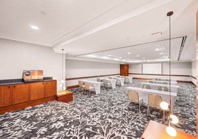 Duxton 2 conference room with tables, chairs, and a projector screen at Duxton Hotel Perth