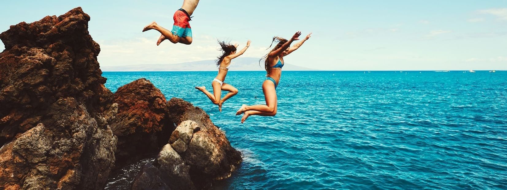 Three people jumping off the cliff at Daydream Island Resort