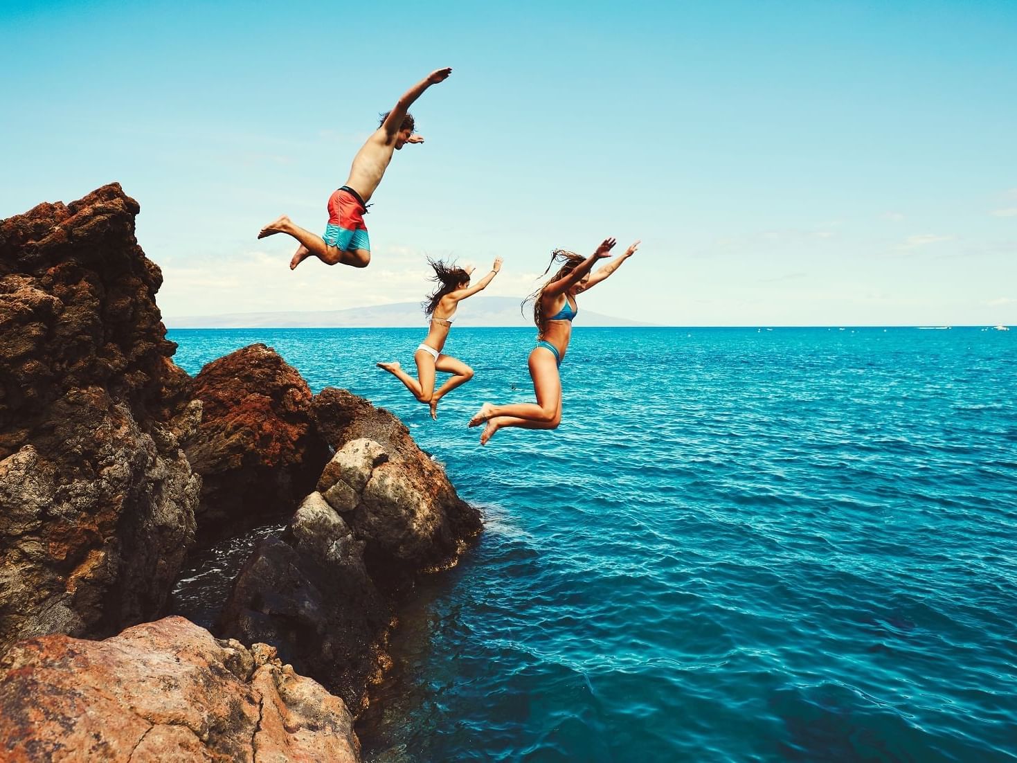 Three people jumping off the cliff at Daydream Island Resort