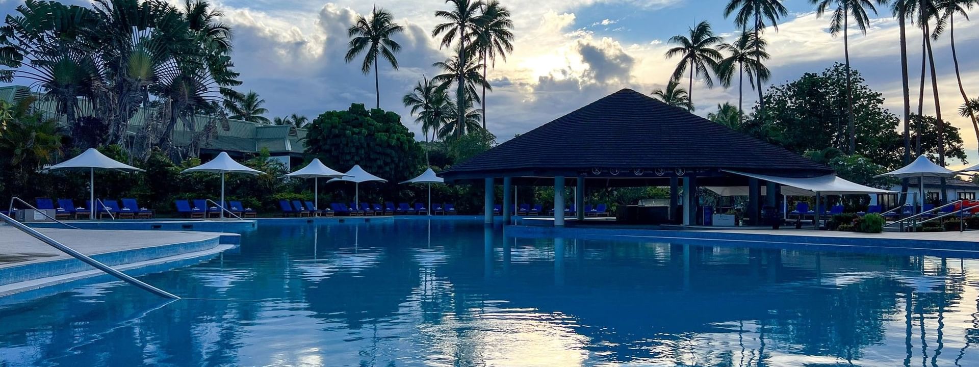 Clear blue swimming pool with palm trees at The Naviti Resort - Fiji in Korolevu
