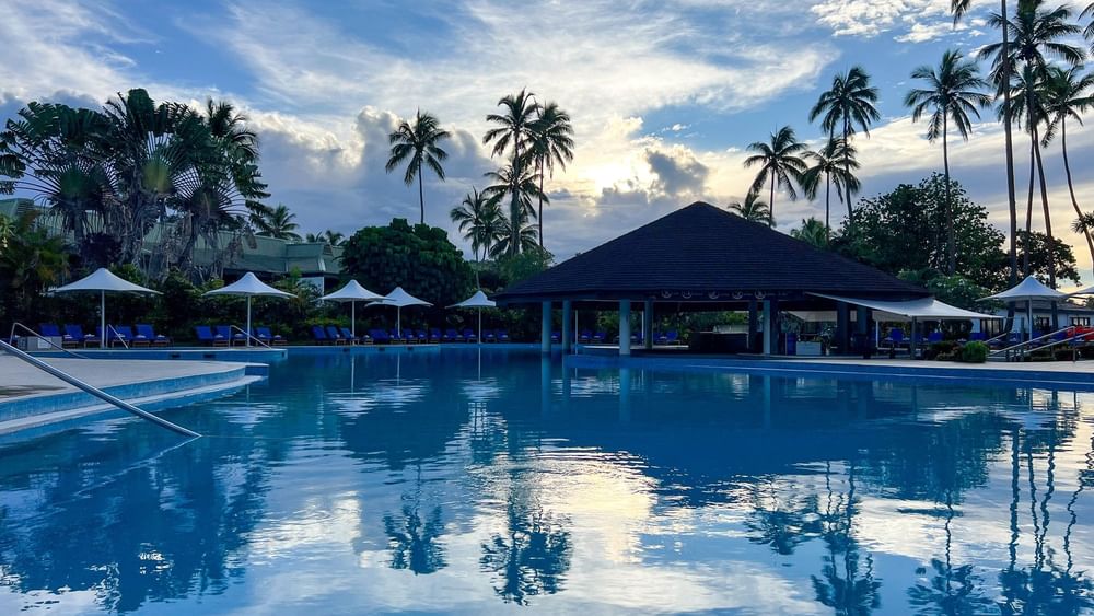Clear blue swimming pool with palm trees at The Naviti Resort - Fiji in Korolevu.