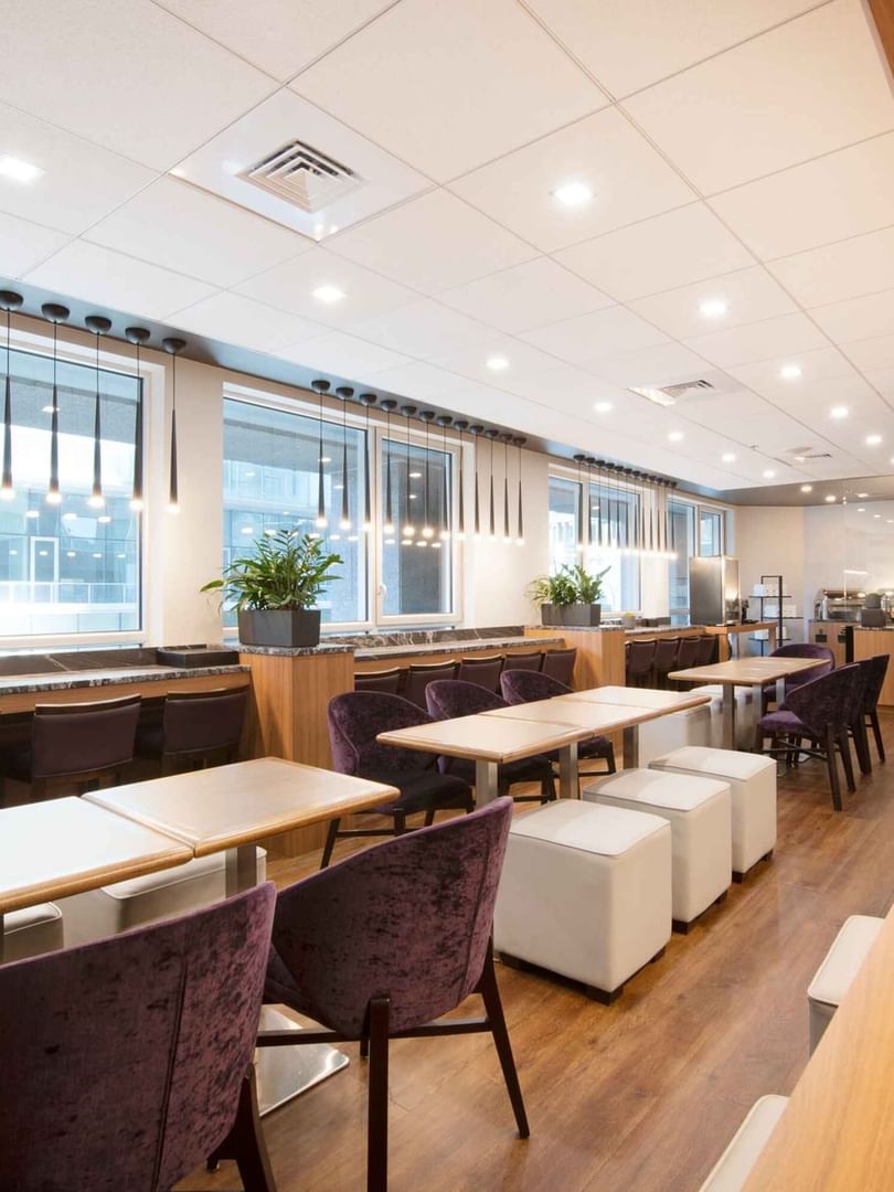 Salon ou espace petit-déjeuner élégant dans les hôtels et complexes Warwick, avec de longues tables communes et des sièges de bar.