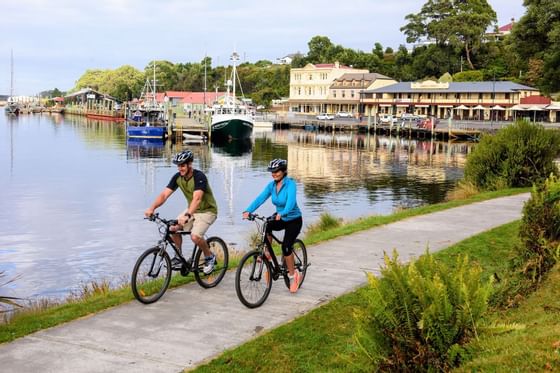 Couple riding bicycles near Hilltop harbor at Strahan Village